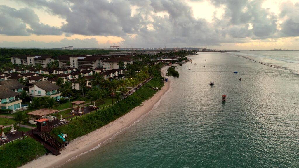 Foto aérea capturada com drone DJI Mini 4 Pro mostrando a orla de um resort em Ipojuca, Pernambuco, com a praia e o mar ao fundo.