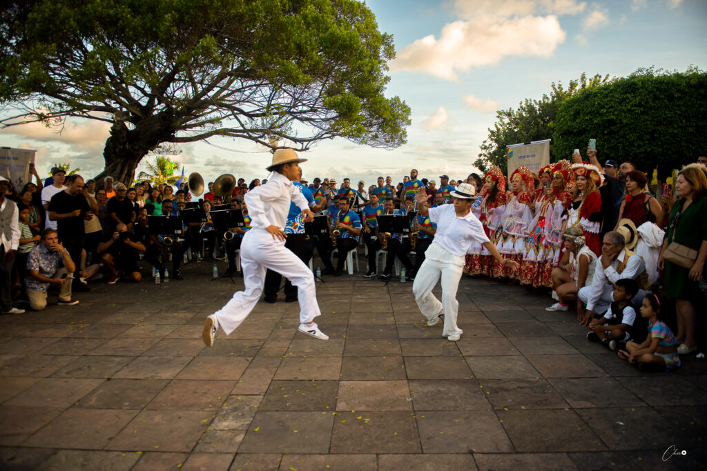 Dois passistas dançando frevo próximo ao pôr-do-sol, em Olinda-PE, no melhor horário para fotografia.